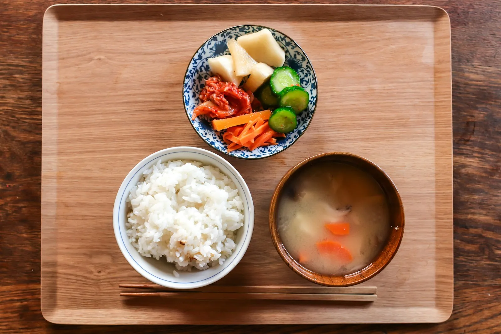 木のトレーに、ごはん・具だくさんの汁もの・漬けものが並んだ一汁一菜の夕飯